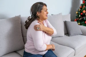 A female patient feeling the symptoms of shoulder stiffness and exploring treatment options with her doctor.