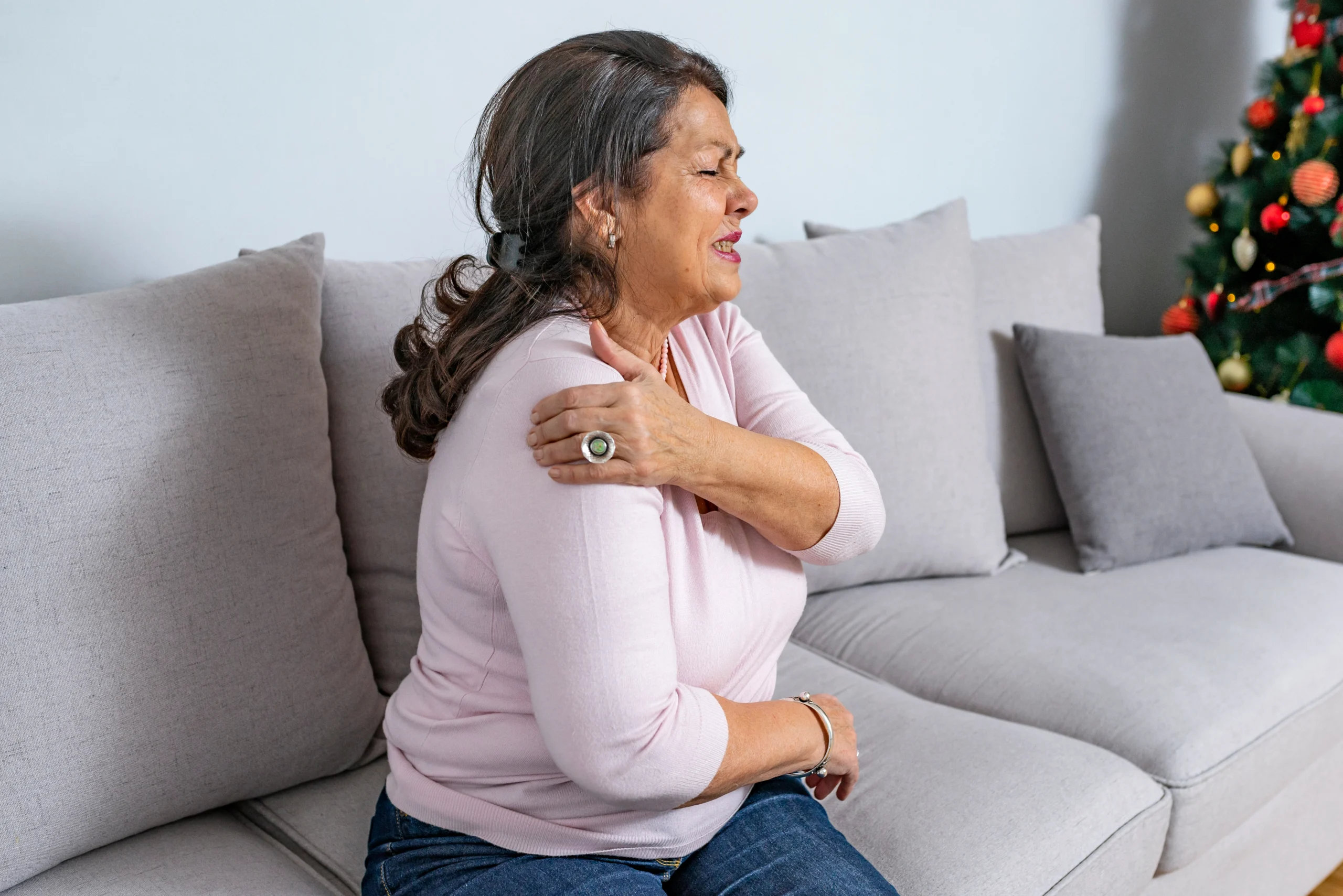A female patient feeling the symptoms of shoulder stiffness and exploring treatment options with her doctor.